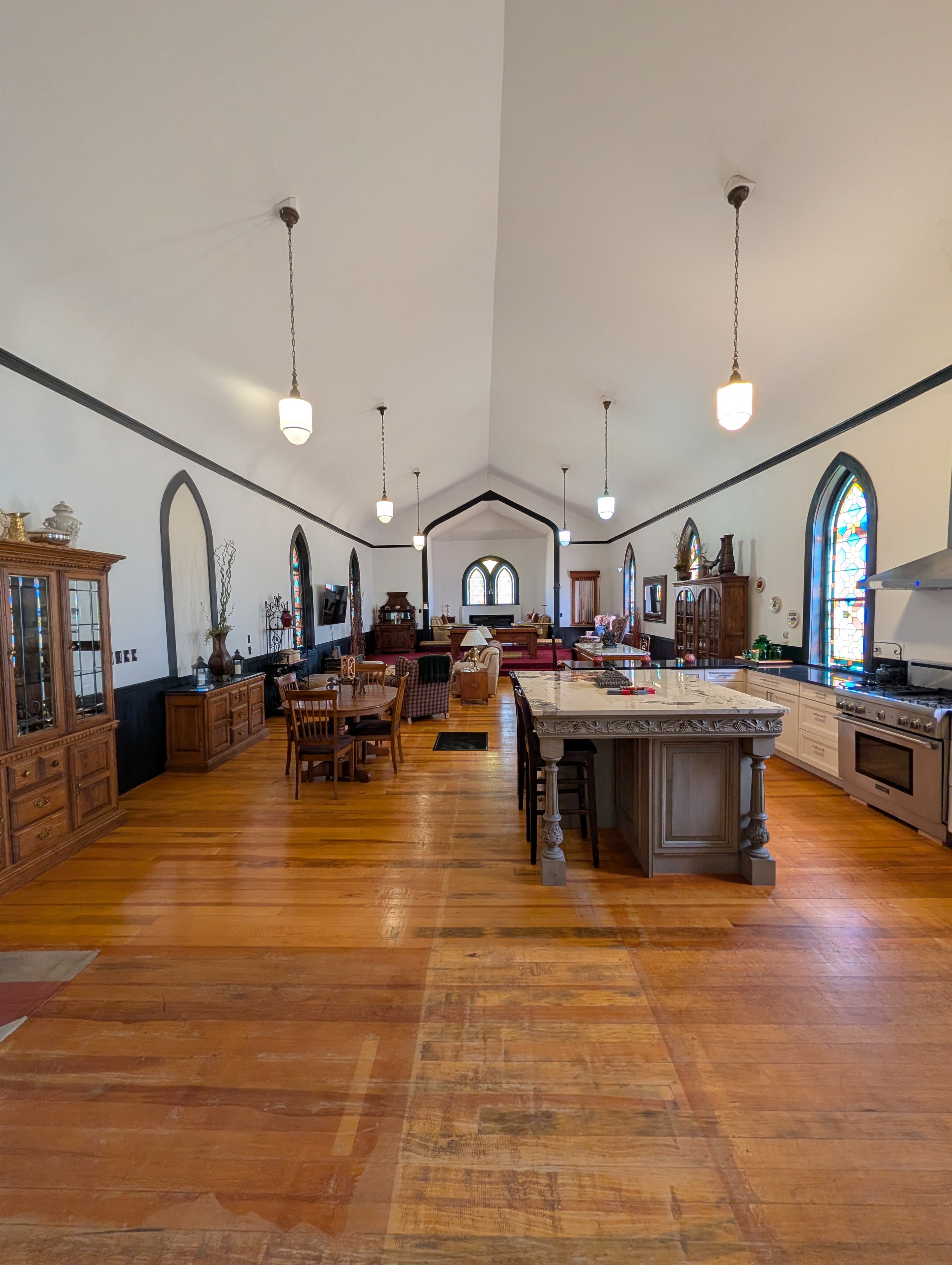 Grand chapel interior with vaulted ceiling, kitchen island, stained glass, and hardwood floors