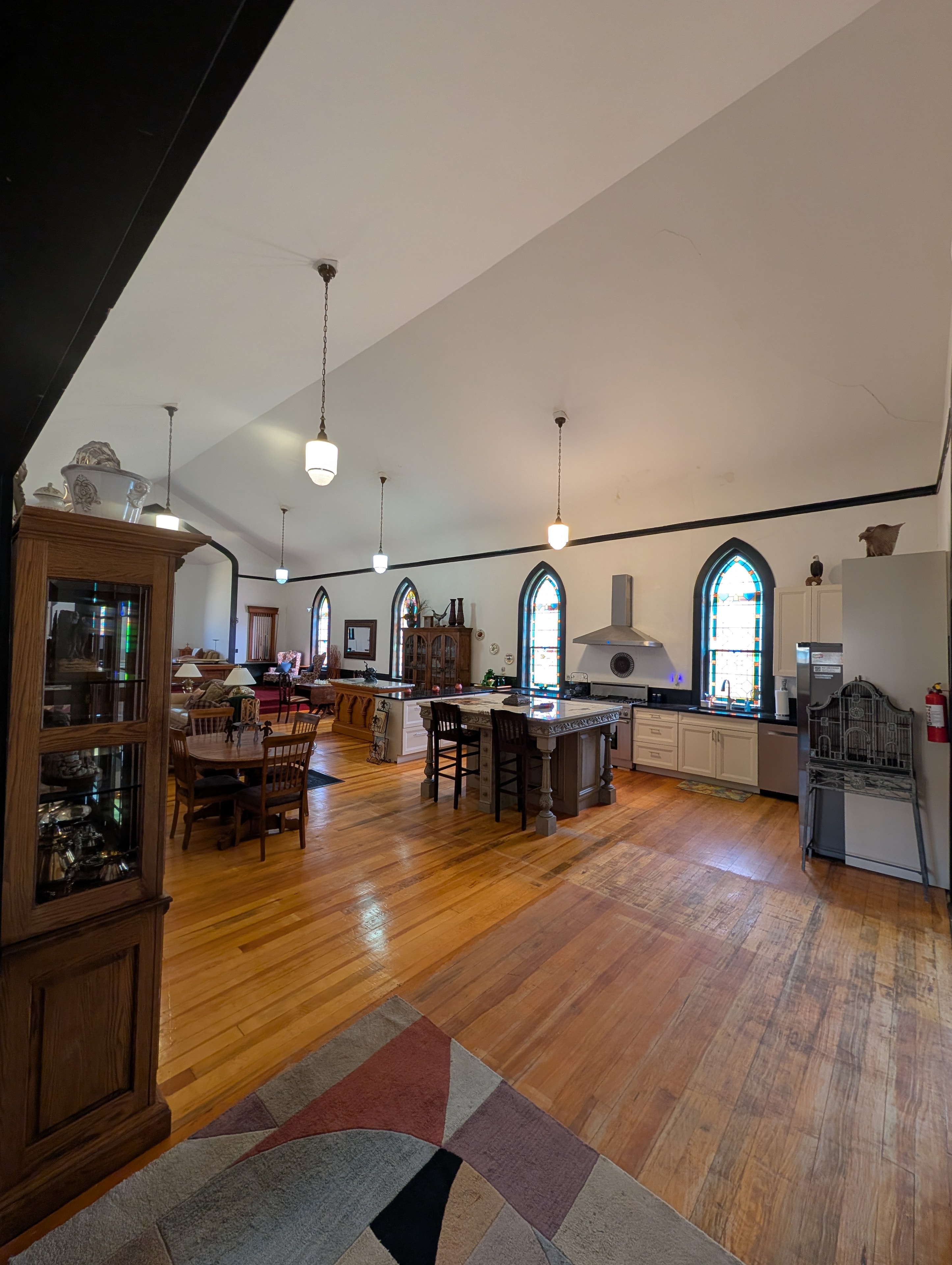 Open chapel gathering space with kitchen, dining area, and arched stained glass windows