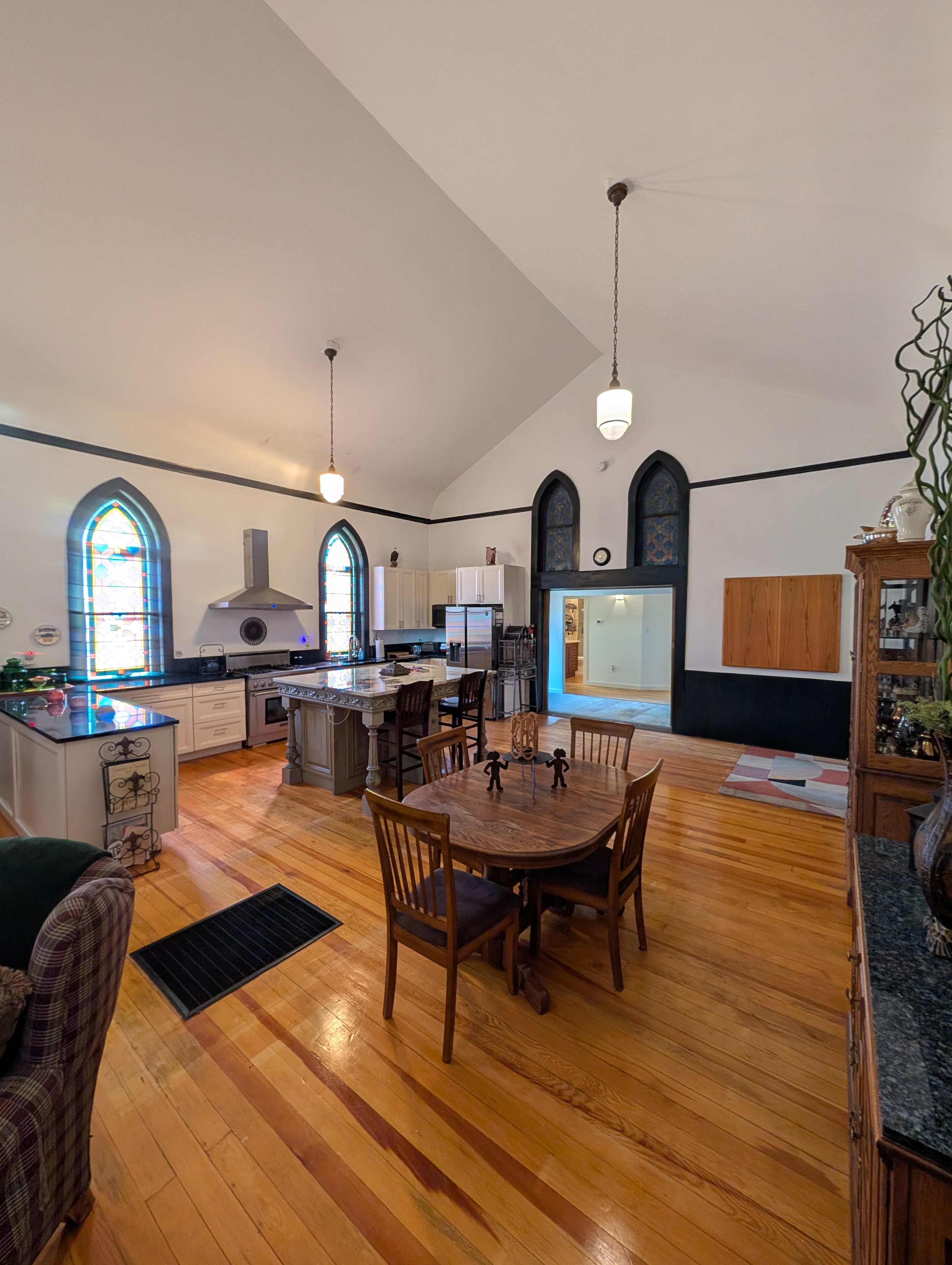 Kitchen and dining area with stained glass windows, marble island, and hardwood floors