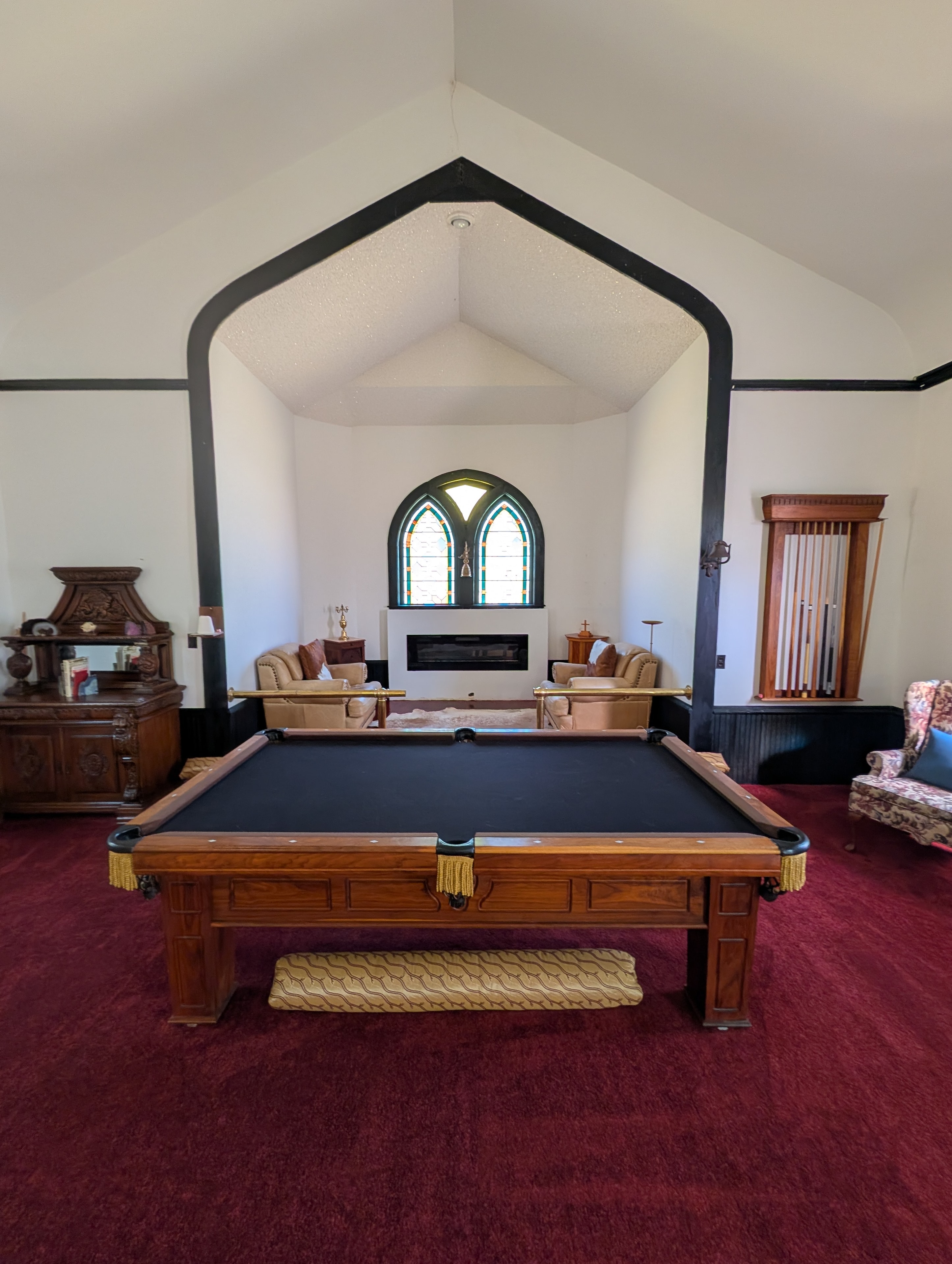 Pool table and lounge area with fireplace and original arched stained glass windows