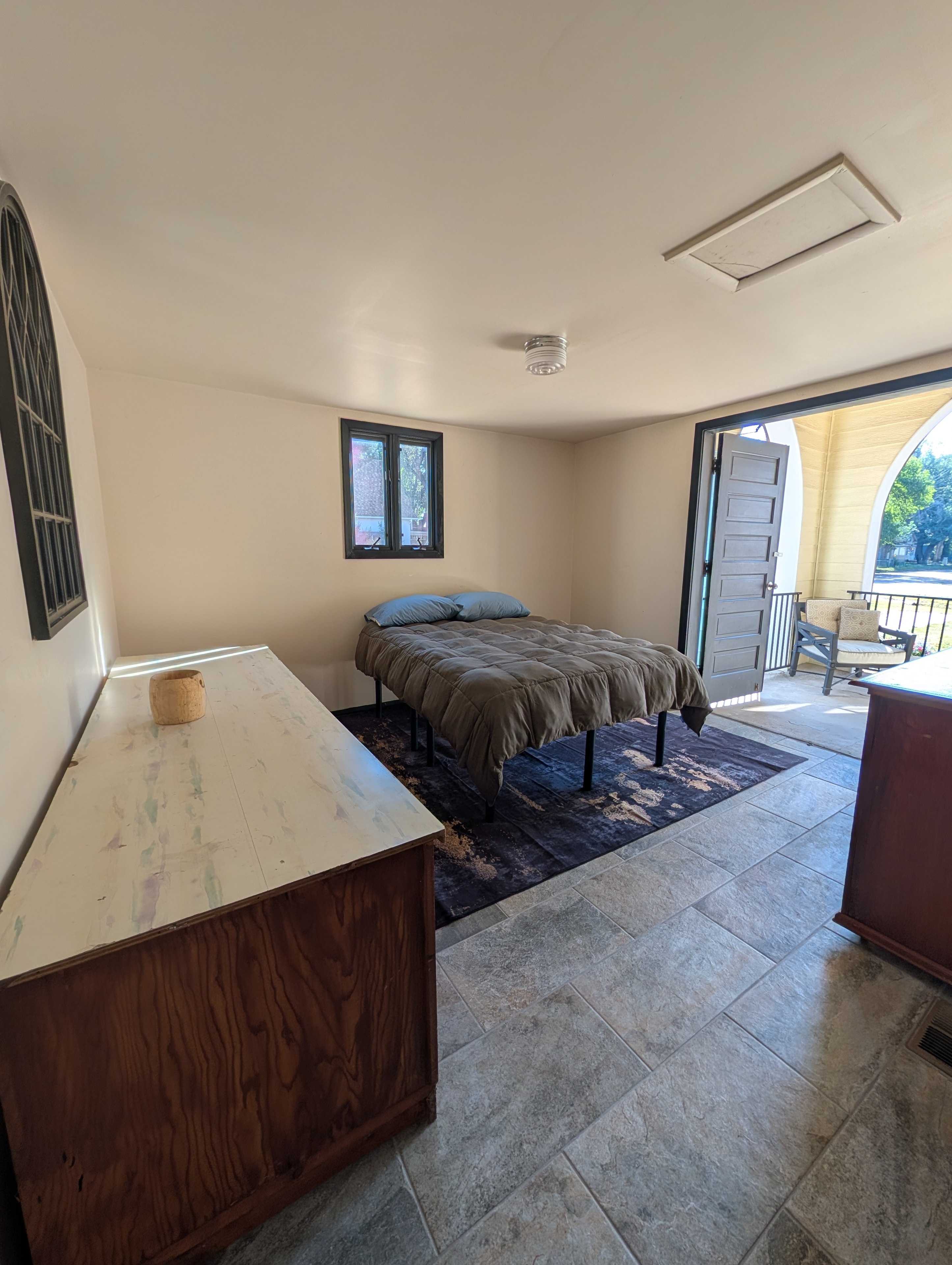 Bedroom with queen bed, tile floors, and arched stained glass window