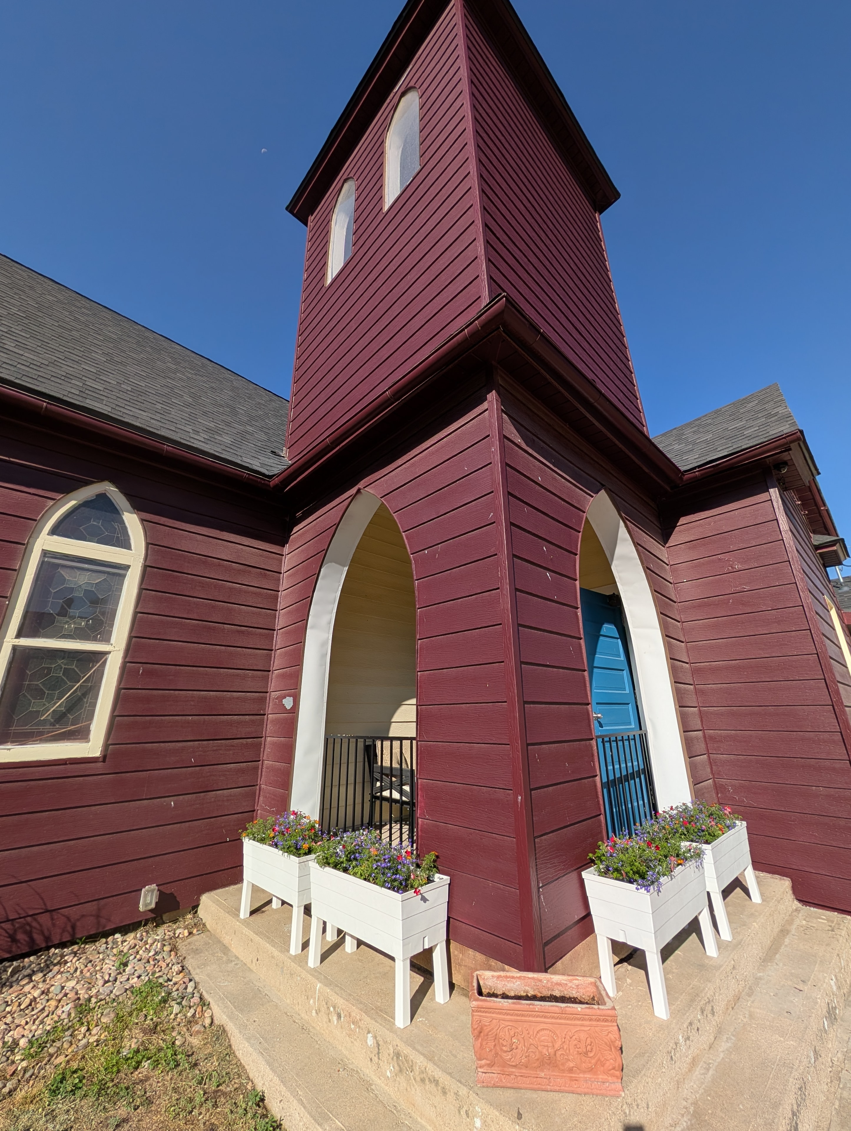 Chapel entrance close-up with white flower planters and blue door