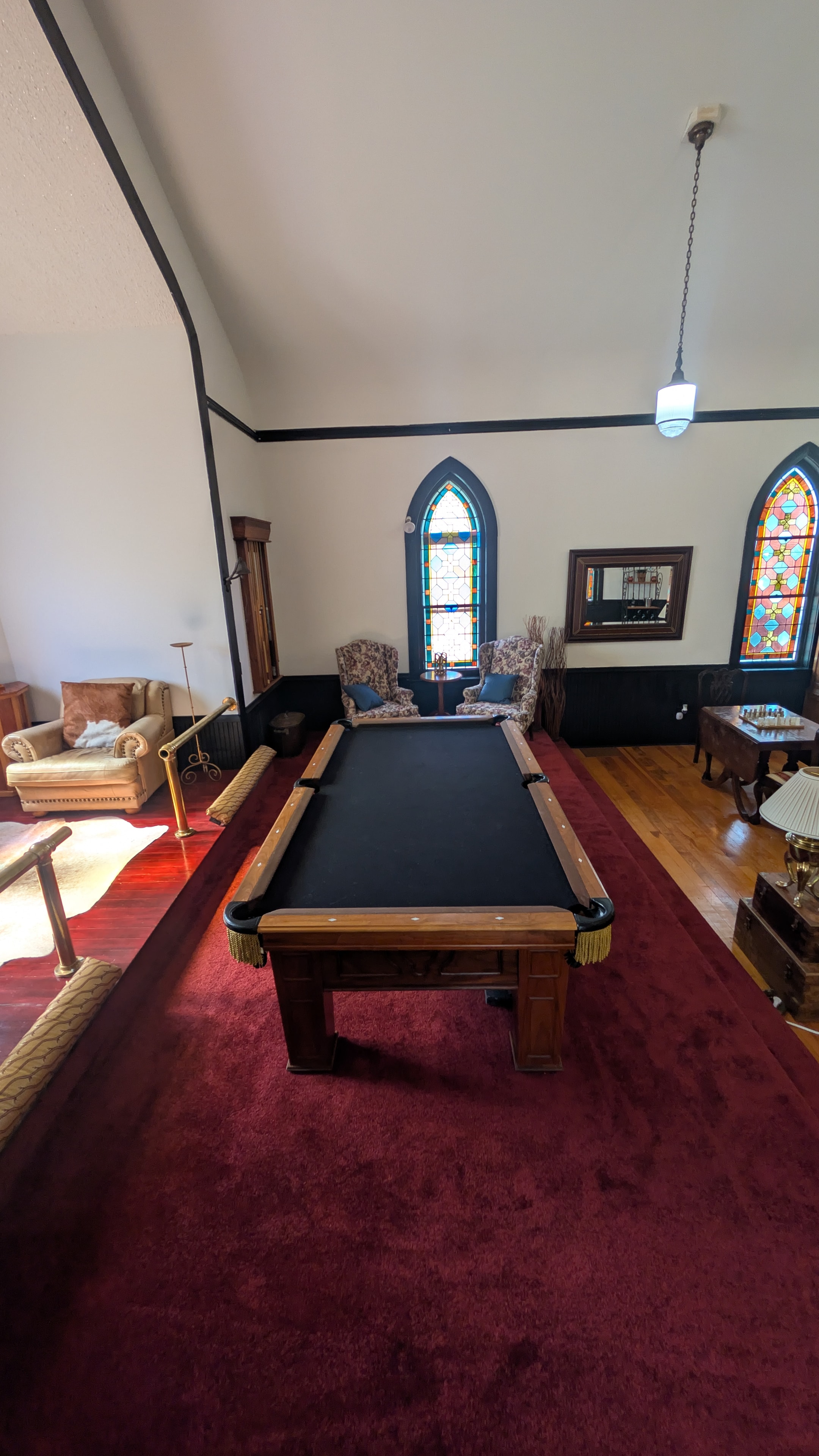 Pool table and lounge area with fireplace and original arched stained glass windows
