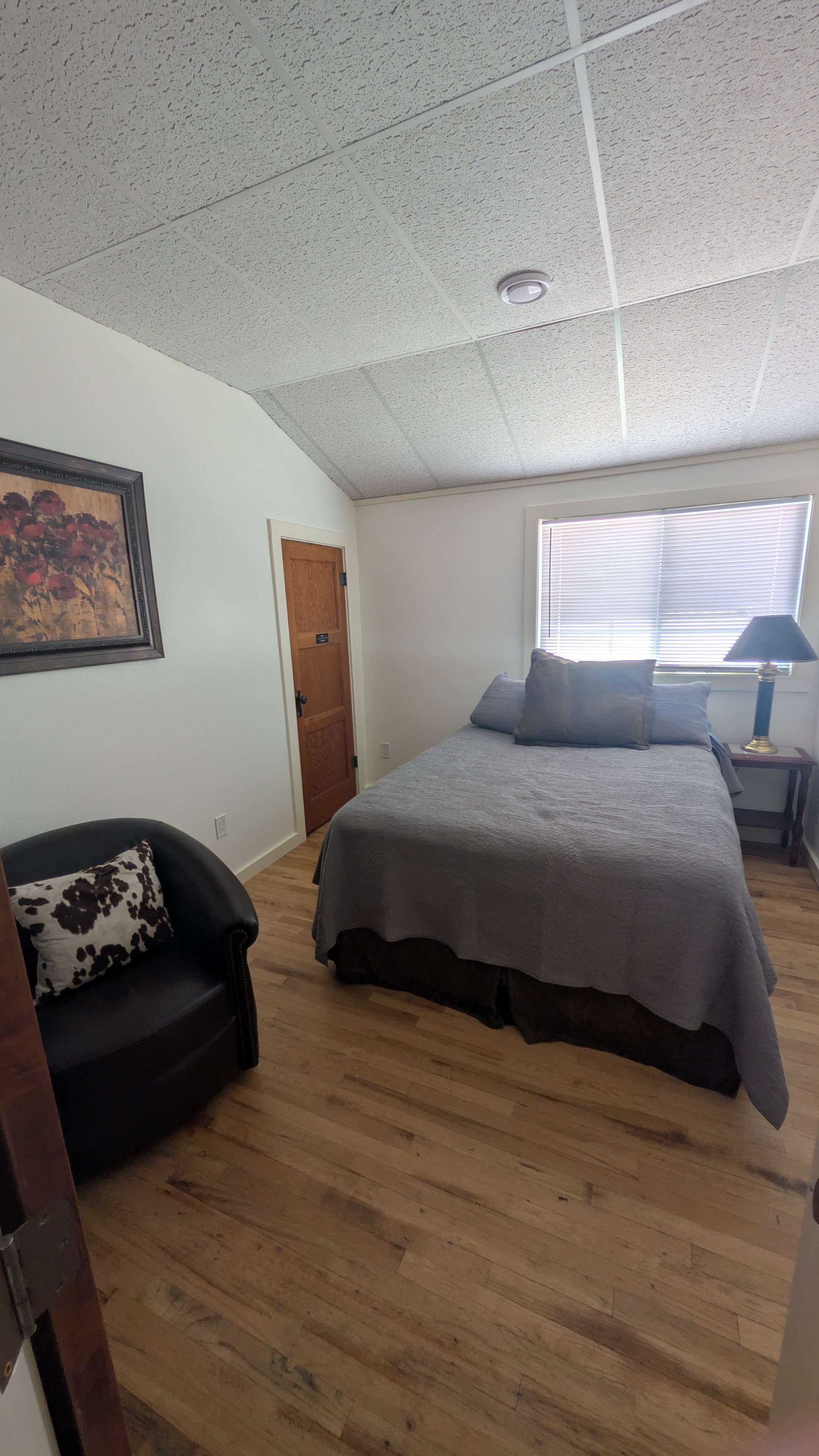 Queen bedroom with hardwood floors and sitting chair